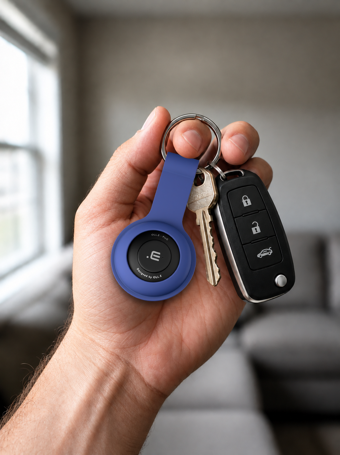 Fits on your keyring — a hand holding a Mint PinG on a ring of house keys, a living room out of focus behind